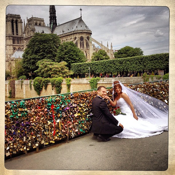 Newlyweds installing their love locks on the bridge behind the Notre Dame.